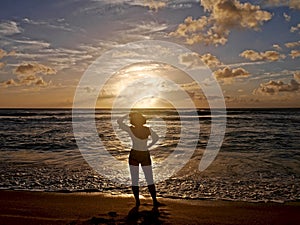Woman silhouette against ocean at sunset.