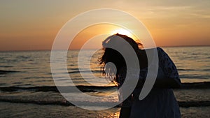 Woman silhouette dancing and jumping on sunset beach