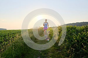 Woman Silhouette with a dog running down a gravel path at sunset