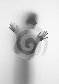Woman silhouette of face and hands behind a diffuse surface