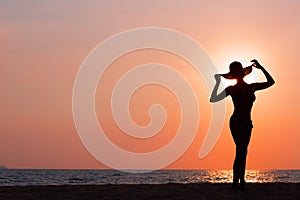Woman silhouette with hat standing on sea background
