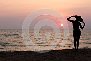 Woman silhouette with hat standing on sea background