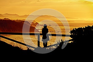 Woman silhouette having fun on the beach at the sunset time. Concept of summer vacation