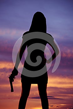 Woman silhouette hold gun by side