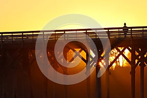 Woman silhouette on pier at sunset