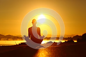 Woman silhouette practicing yoga exercise at sunrise