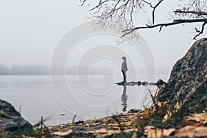 Woman silhouette on the river bank in the morning fog