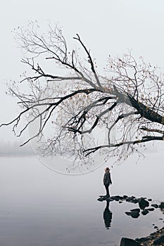 Woman silhouette on the river bank in the morning fog