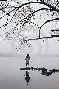 Woman silhouette on the river bank in the morning fog