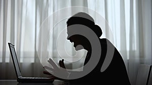 Woman silhouette screaming and closing laptop during work at night, overstrain