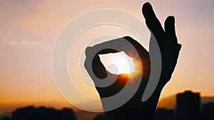 Woman silhouette is showing hand sign gesture OK against the sunset, sunrise sky