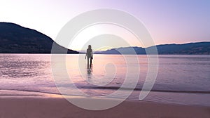 Woman in silhouette standing in lake at sunset