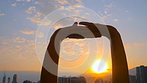 Woman silhouette is stretching arms up against the sunrise sky: close up