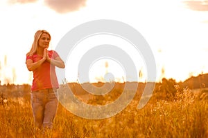 Woman silhouette waiting for summer sun on meadow