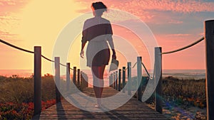 Woman silhouette in a wooden foot bridge at the beach at sunset