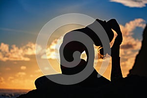 Woman silhouette in yoga pose on sunset sea beach