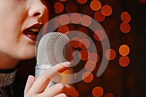 Woman singer with disco mic on bokeh light background.