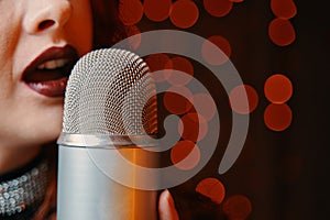 Woman singer with disco mic on bokeh light background.