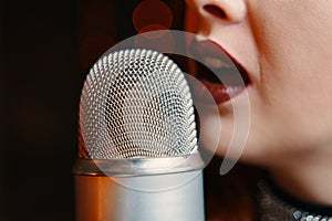 Woman singer with disco mic on bokeh light background.