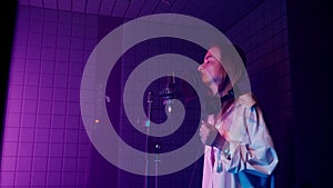 woman is singing lyric song in professional recording studio, standing near mic in isolation booth