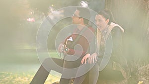 Woman singing and man playing guitar while sitting on a tree in park