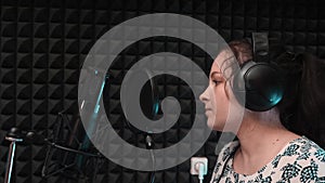 Woman singing in music studio. Black microphone and pop filter in music studio