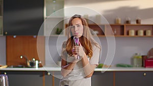 Woman singing song in whisker on kitchen. Lady dancing at home