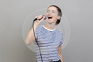 Woman singing songs at karaoke, having fun, holding microphone, entertainment.