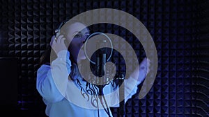 Woman singing into sound microphone in dark record studio. Singer vocalist performing song. Female singer recording new lyric albu