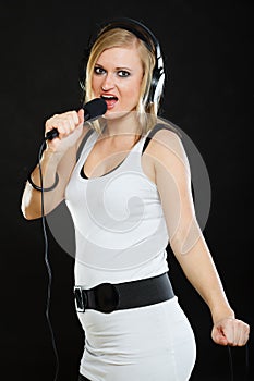 Woman singing to microphone wearing headphones