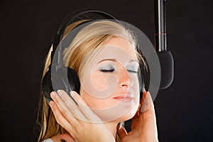 Woman singing to microphone wearing headphones in studio