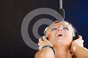 Woman singing to microphone wearing headphones in studio