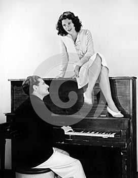 Woman singing on an upright piano with a friend playing