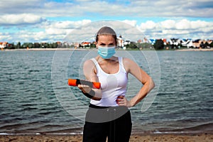 Woman in singular mask do exercises on the beach