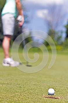 Woman sinking a putt on a golf green - selective focus
