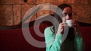 Woman sipping coffee in a cozy cafe setting during the evening. A contemplative woman enjoys a warm cup of coffee