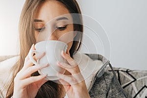 Woman sipping coffee or tea from white mug in the morning