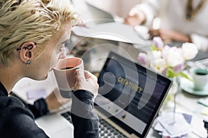 Woman Sipping Coffee while Working on Laptop