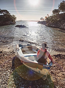 Woman sit in boat on bank of sea and dreaming