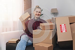 Woman sit on couch at home with lot of cardboard boxes