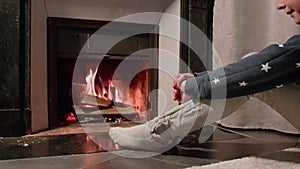 Woman sit in front of fireplace looking at fire getting warm