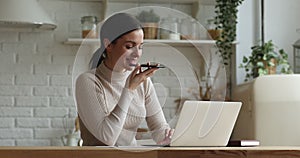 Woman sit in kitchen using smart phone talk on speakerphone