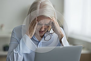 Woman sit near laptop take off glasses suffers from migraine