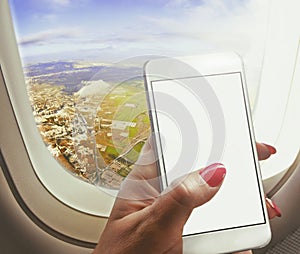 Woman sit near window , holding smart-phone working on board of airplane