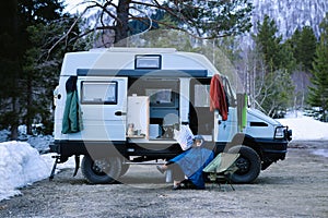 Woman sit next to overlanding 4x4 camper van