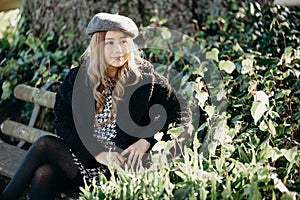 Woman sit on a park bench, leisure time in autumn park. fashion woman in black coat sitting on a bench