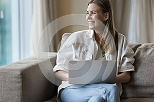 Woman sit on sofa with laptop, smile, enjoy on-line communication
