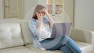 Woman sit on sofa with laptop and talking on phone. shares feelings with friend.
