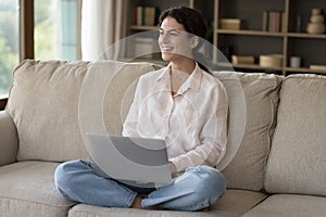 Woman sit on sofa with notebook smile looks aside