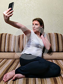 woman sit on sofa and take selfie at home